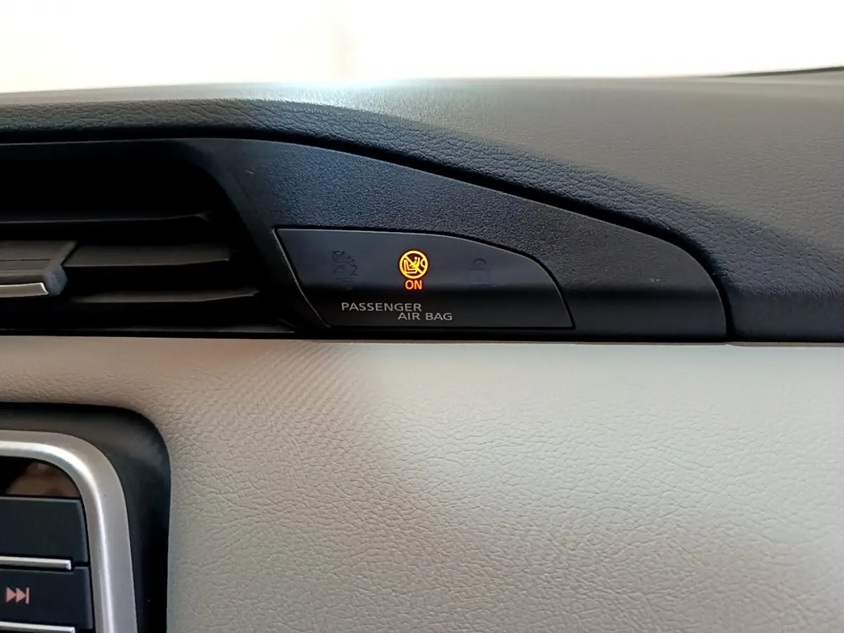 Gros plan sur le tableau de bord beige et noir de la Nissan Micra 2022, voyant airbag passager allumé en orange.