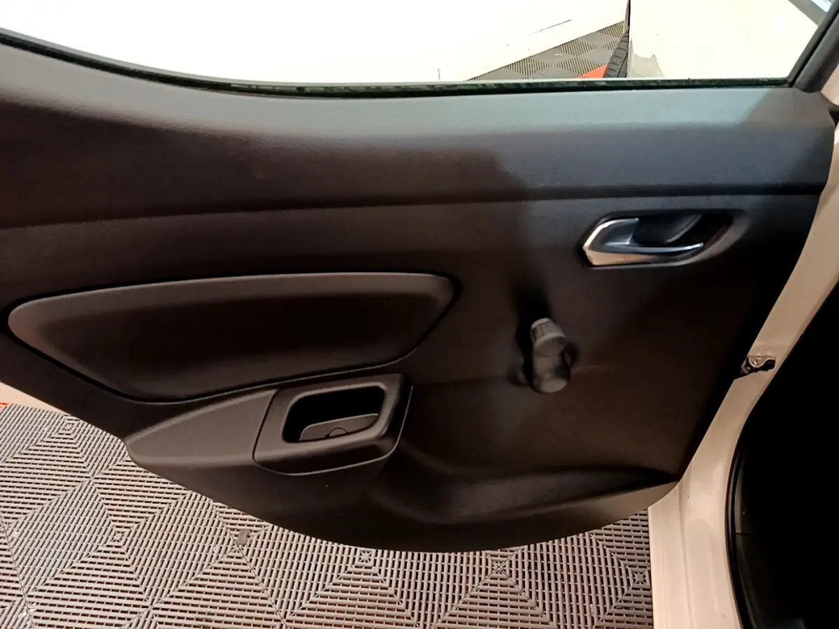 Vue intérieure sur la porte côté droit noire d'une Nissan Micra blanche 2022 avec poignée et manivelle de vitre.