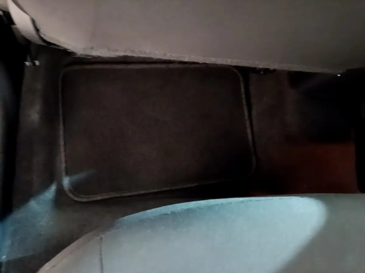 Vue rapprochée du tapis de sol noir au niveau du plancher arrière d'une Nissan Micra IG-T 92 Acenta blanche.