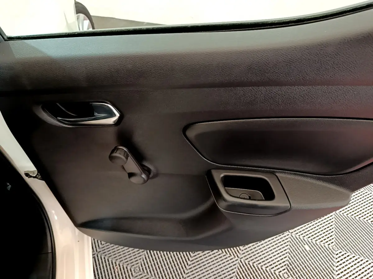 Vue rapprochée de la porte intérieure côté gauche d'une Nissan Micra blanche 2022, avec poignée et manivelle de vitre.