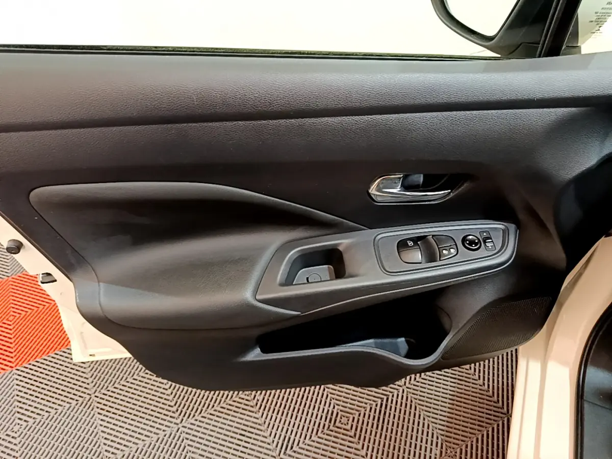 Vue intérieure côté gauche de la porte avant d'une Nissan Micra blanche 2022 avec commandes électriques et poignée chrome.