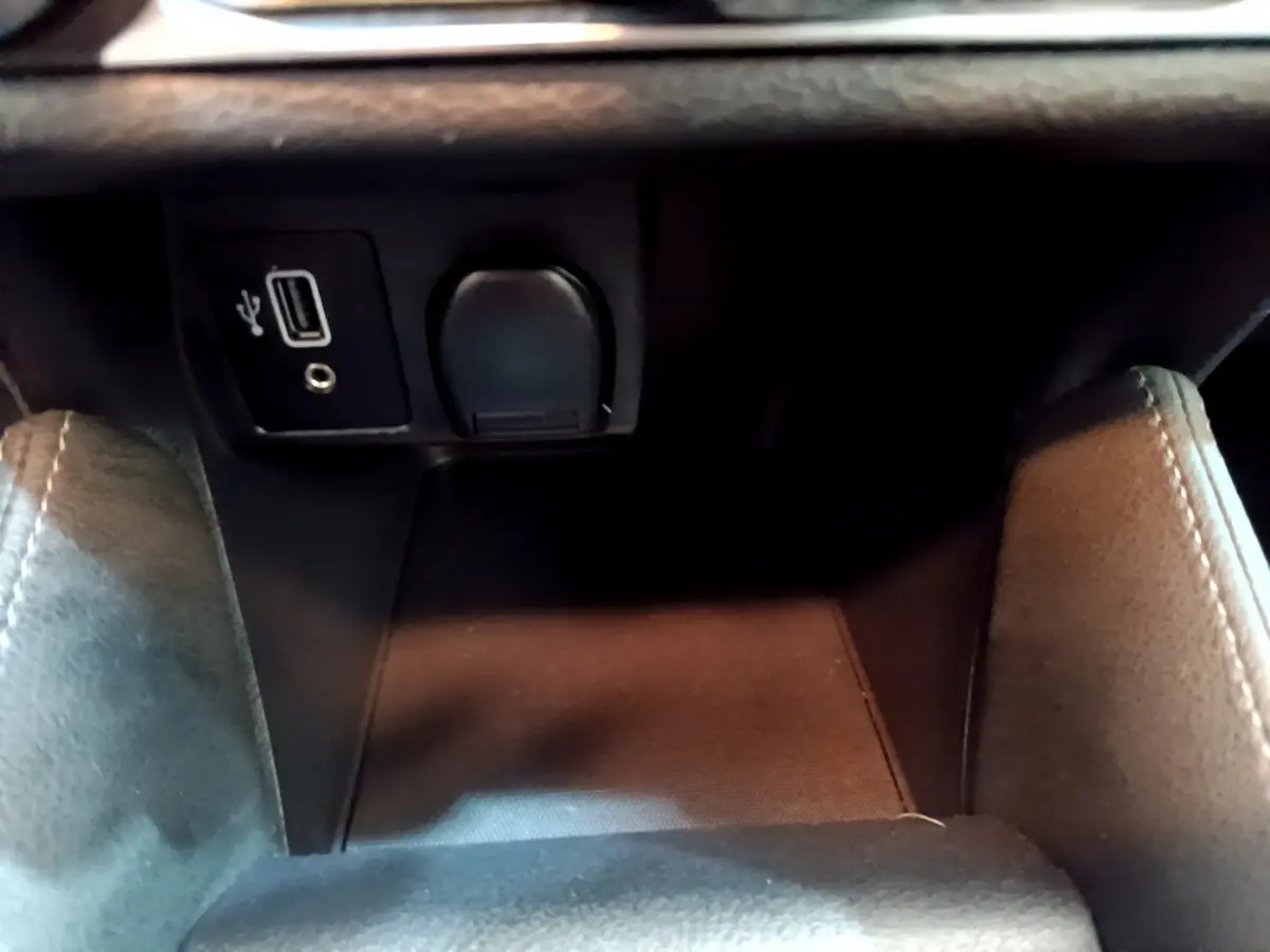 Prise USB et prise 12V noires dans le compartiment central avant de la Nissan Micra blanche IG-T 92 Acenta 2022.