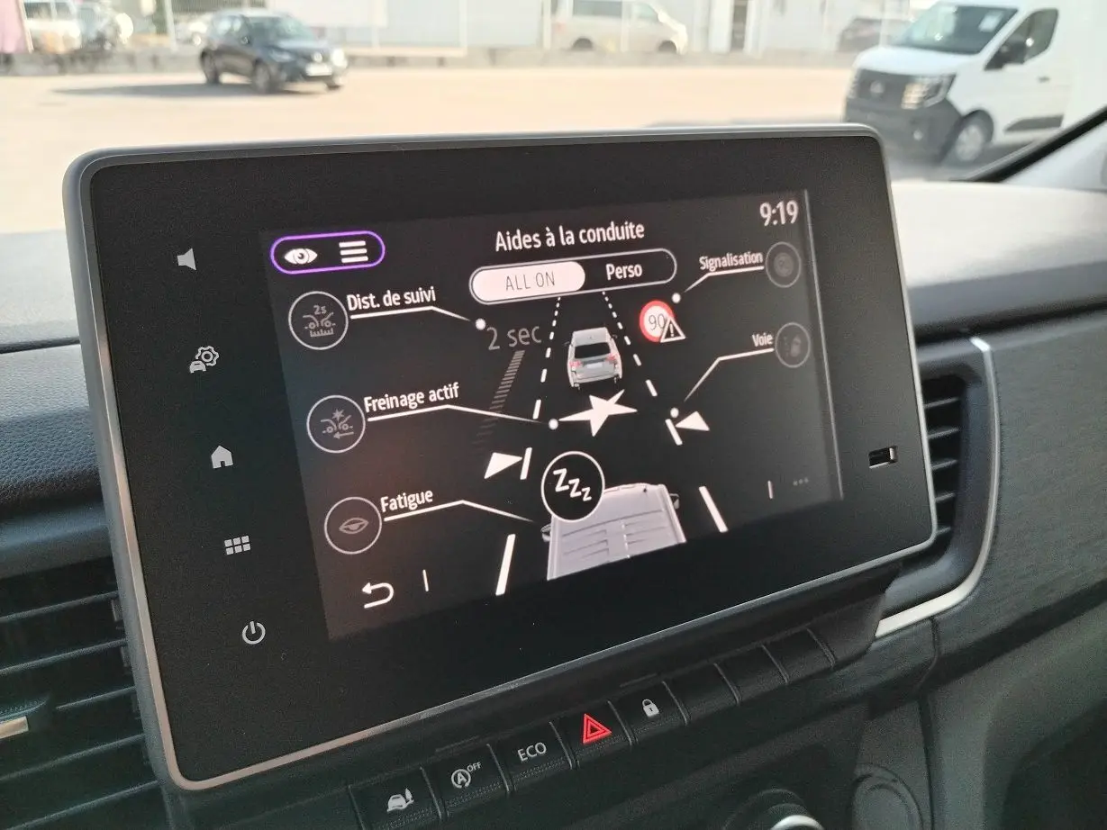 Écran tactile intérieur du Nissan Primastar 2025 montrant les aides à la conduite avec vue sur tableau de bord noir.