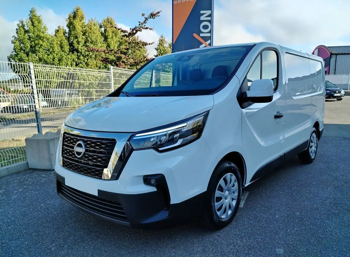 Nissan Primastar blanc en 3/4 avant droit, fourgon utilitaire avec calandre chromée et phares LED modernes.