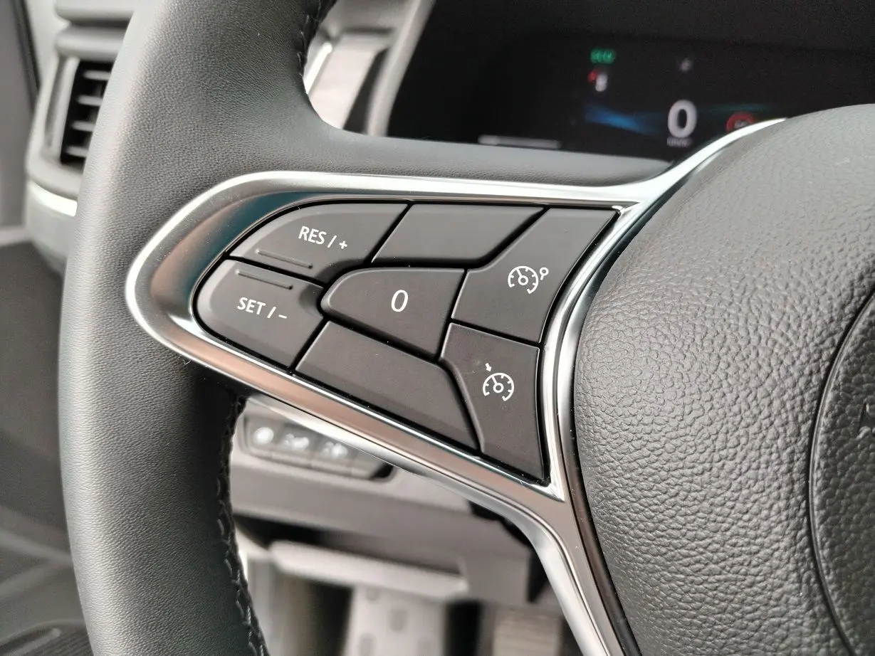 Gros plan sur les commandes de régulateur de vitesse au volant noir du Nissan Primastar 2025.