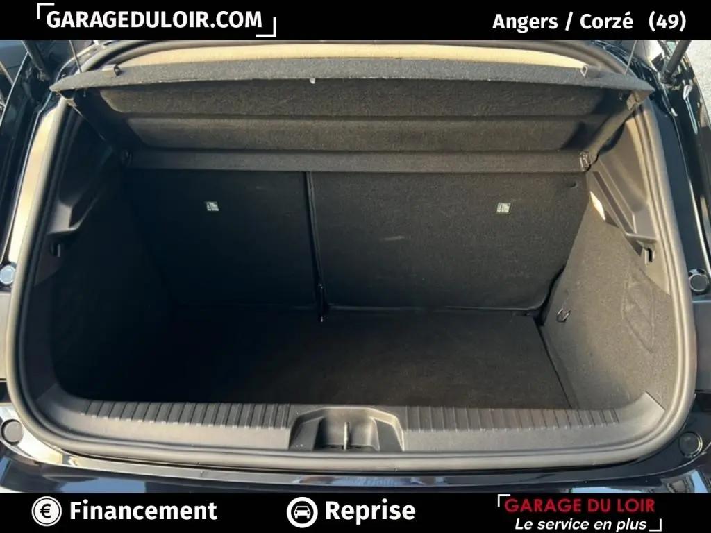 Coffre ouvert vu de l'arrière d'une Renault Clio noire 2025, intérieur spacieux et tapis noir visible.