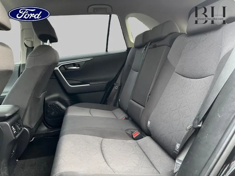 Vue intérieure côté droit montrant la banquette arrière en tissu noir avec motifs géométriques et accoudoir central.