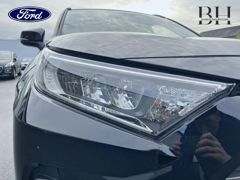 Gros plan sur le phare avant droit du Toyota RAV4 noir métallisé, soulignant ses lignes modernes et précises.