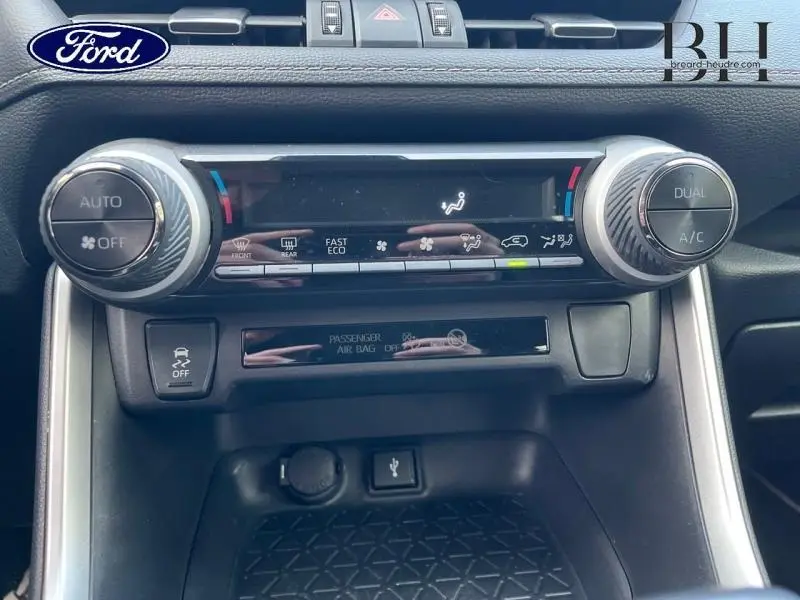 Vue rapprochée de la console centrale du Toyota RAV4 noir, montrant les commandes de climatisation automatique bi-zone.