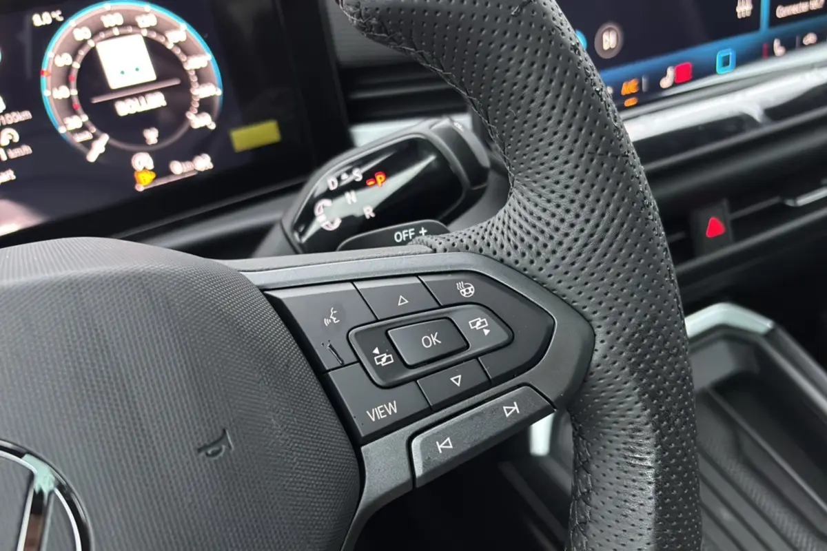Gros plan sur le volant cuir perforé du Volkswagen T-Roc 2026 avec commandes multifonctions et tableau de bord numérique.