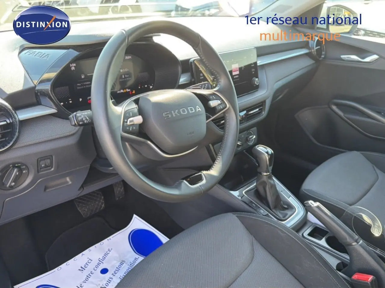 Vue intérieure de face du poste de conduite gris noir de la Skoda Fabia 2025 avec volant multifonction et écran tactile central.