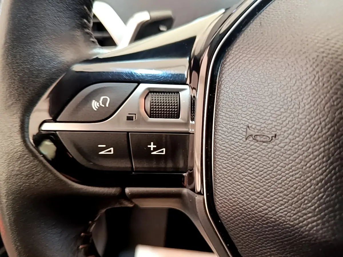 Gros plan sur les commandes gauche du volant en cuir noir du Peugeot 3008 bleu, version Active Pack 2022.