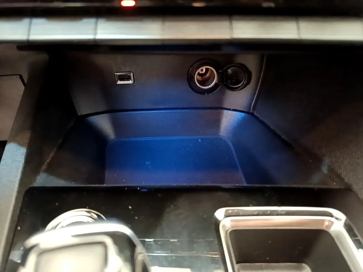 Vue rapprochée de la console centrale noire du Peugeot 3008 2022 avec prise USB et allume-cigare ouverte.