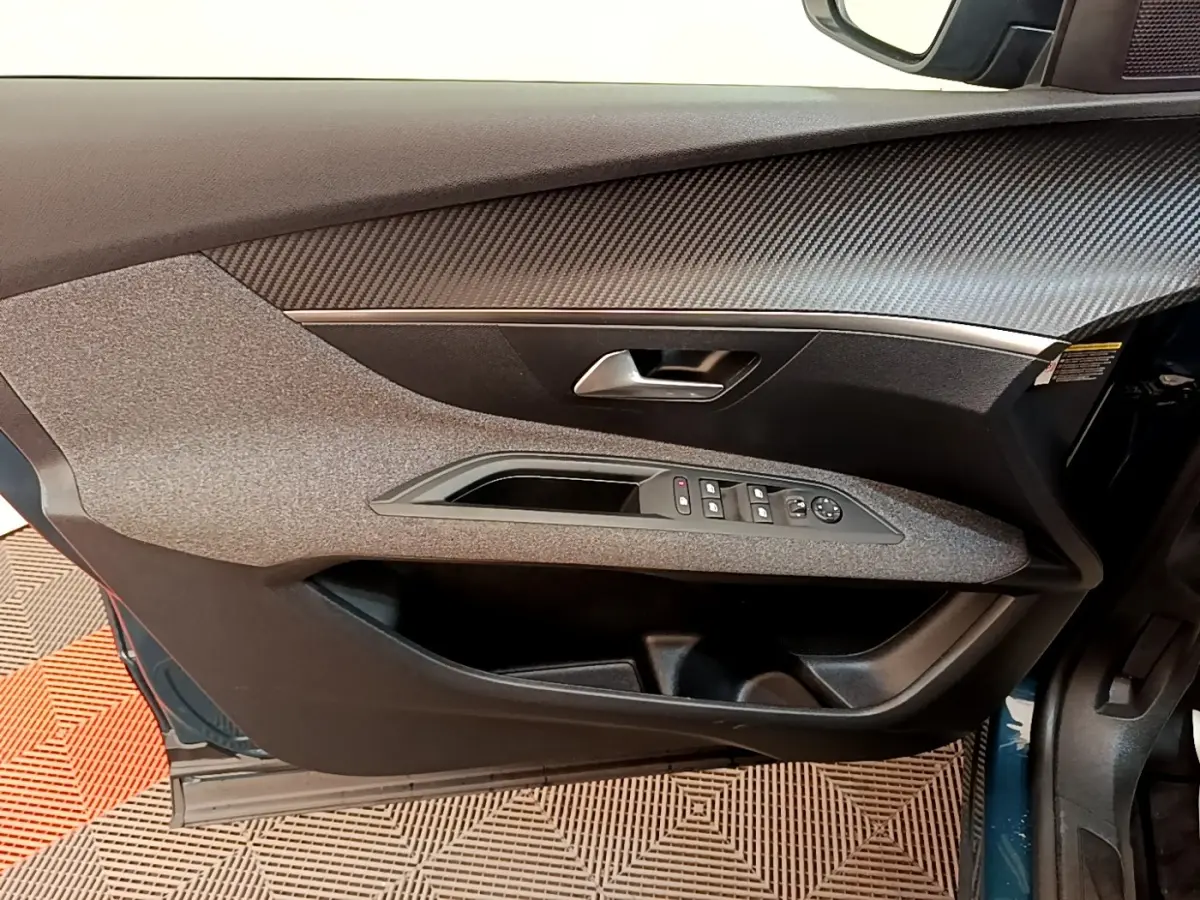 Vue intérieure côté gauche de la porte avant d’un Peugeot 3008 bleu, avec commandes des vitres et poignée argentée.