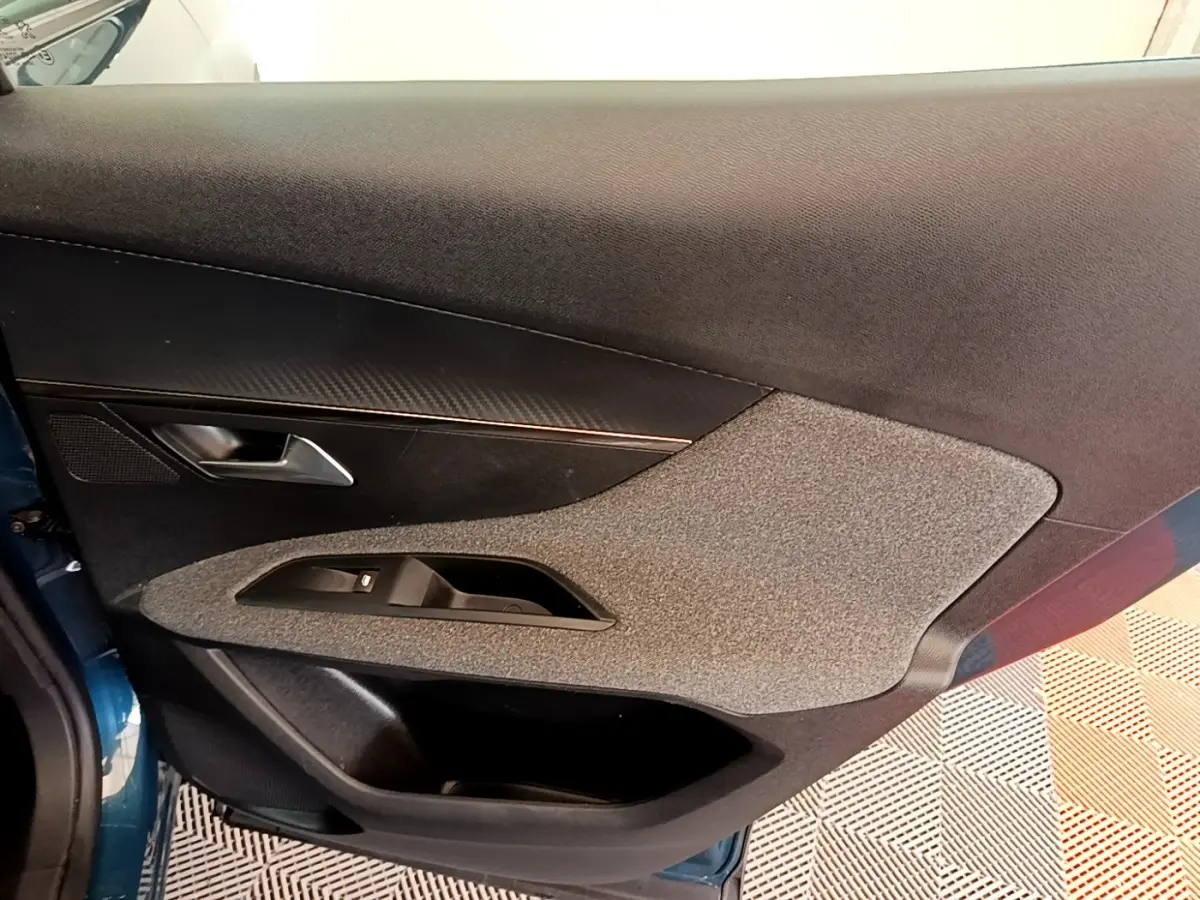 Vue intérieure côté gauche de la porte avant d’un Peugeot 3008 bleu avec garniture tissu et plastique noir.