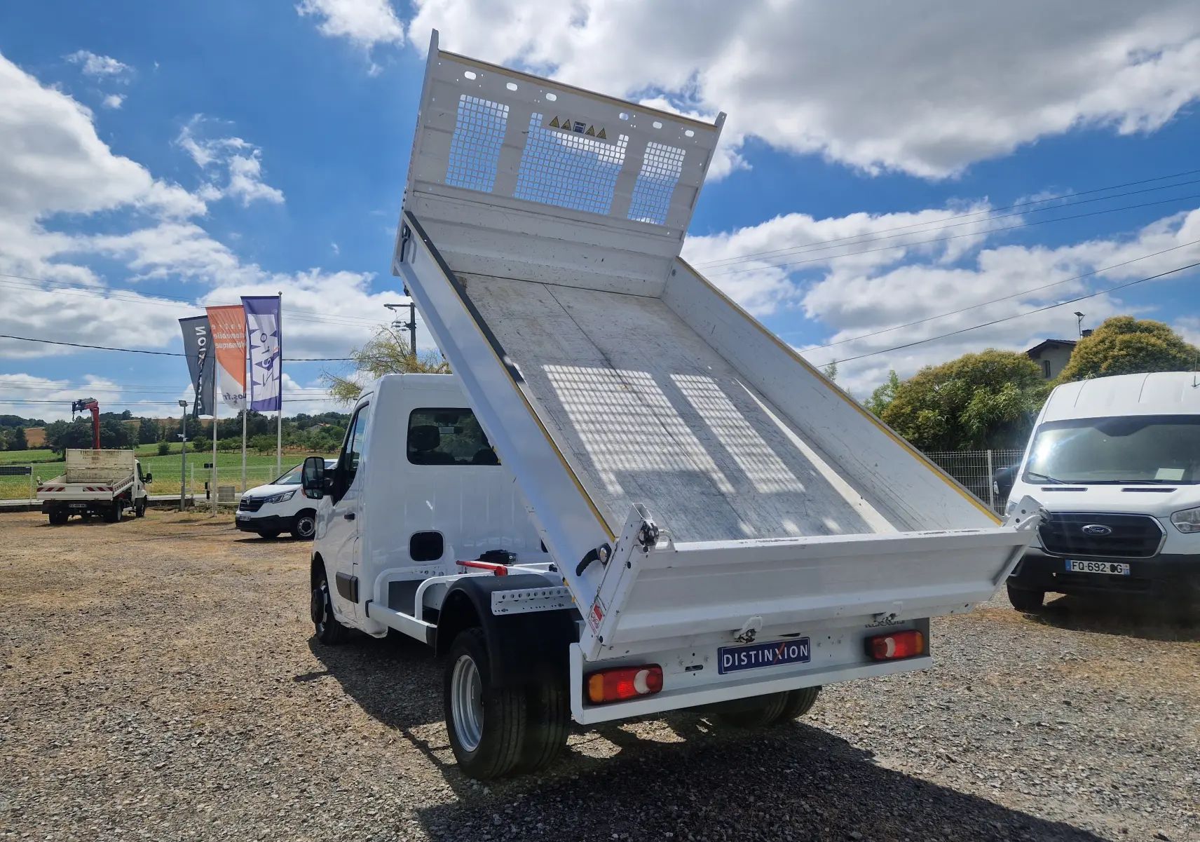 Vue arrière en léger angle droit du Renault Master Châssis Cabine blanc avec benne relevée et roues jumelées visibles.