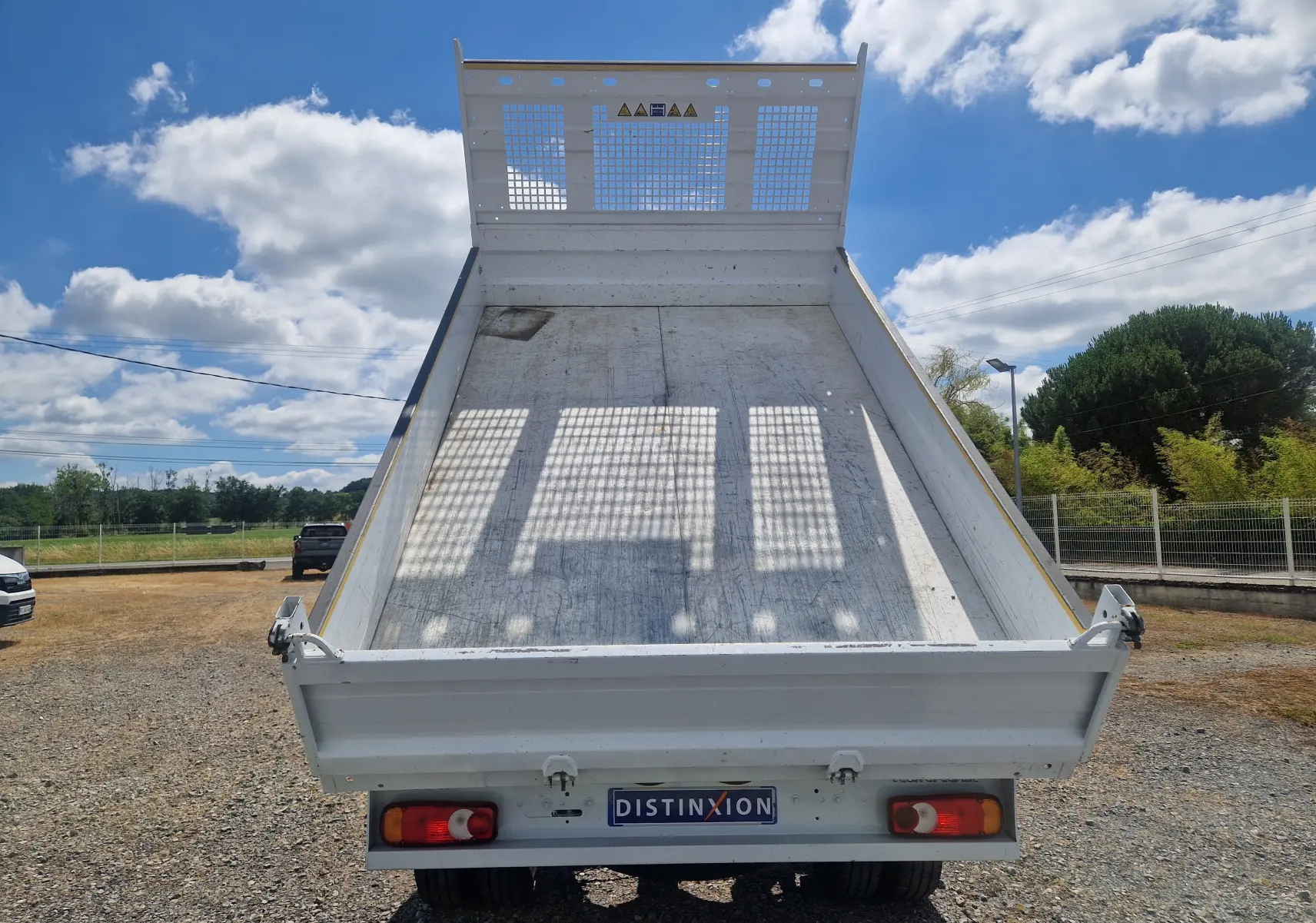 Vue arrière d'une benne blanche relevée d'un Renault Master Châssis Cabine 2024 avec roues jumelées sur terrain extérieur.