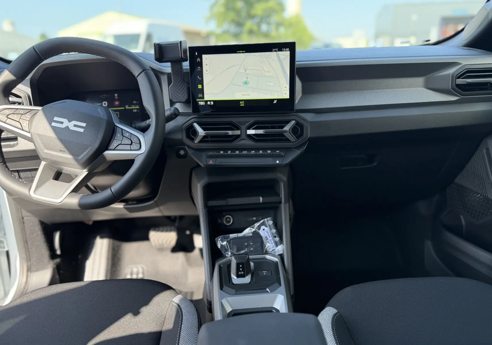 Vue intérieure frontale du tableau de bord du Dacia Duster Hybrid 155 Journey avec écran tactile et volant multifonction noir.