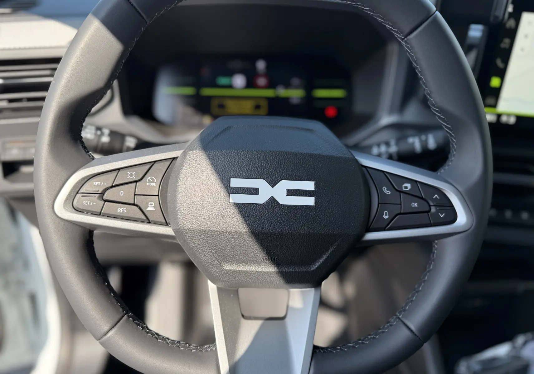 Gros plan sur le volant noir du Dacia Duster Hybrid 155 Journey 2026, avec commandes intégrées et logo central distinctif.