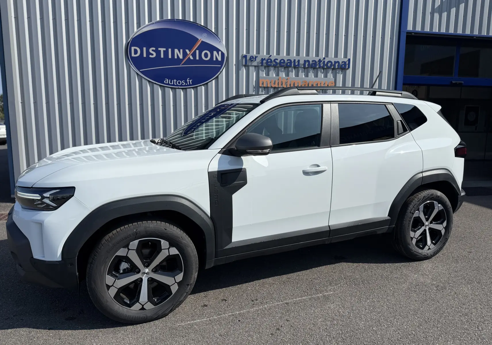 Vue de profil droit du Dacia Duster Hybrid 155 Journey blanc glacier avec jantes noires et détails noirs contrastants.