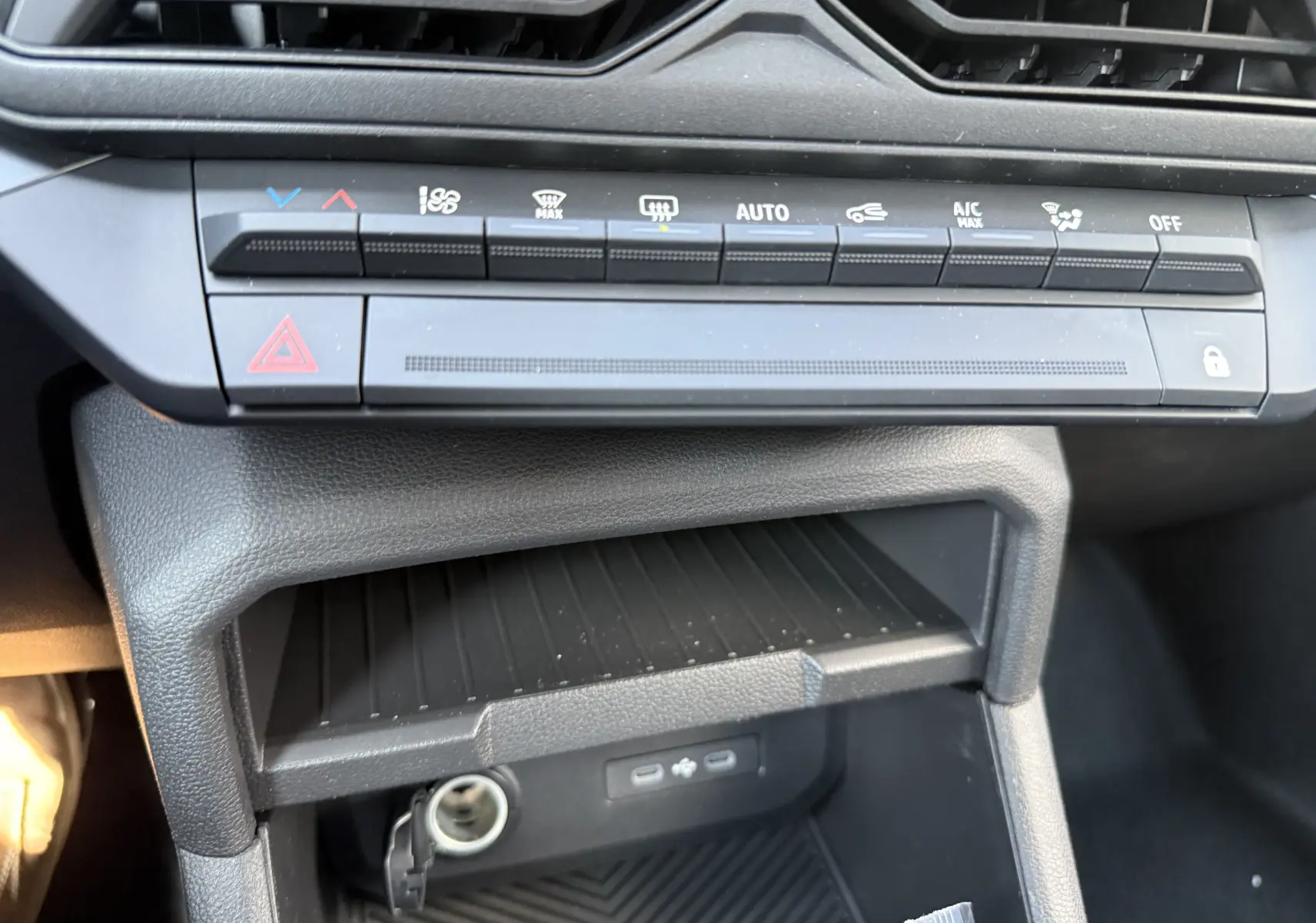 Gros plan sur la console centrale du Dacia Duster Hybrid 155 Journey 2026, montrant les commandes climatisation et ports USB.