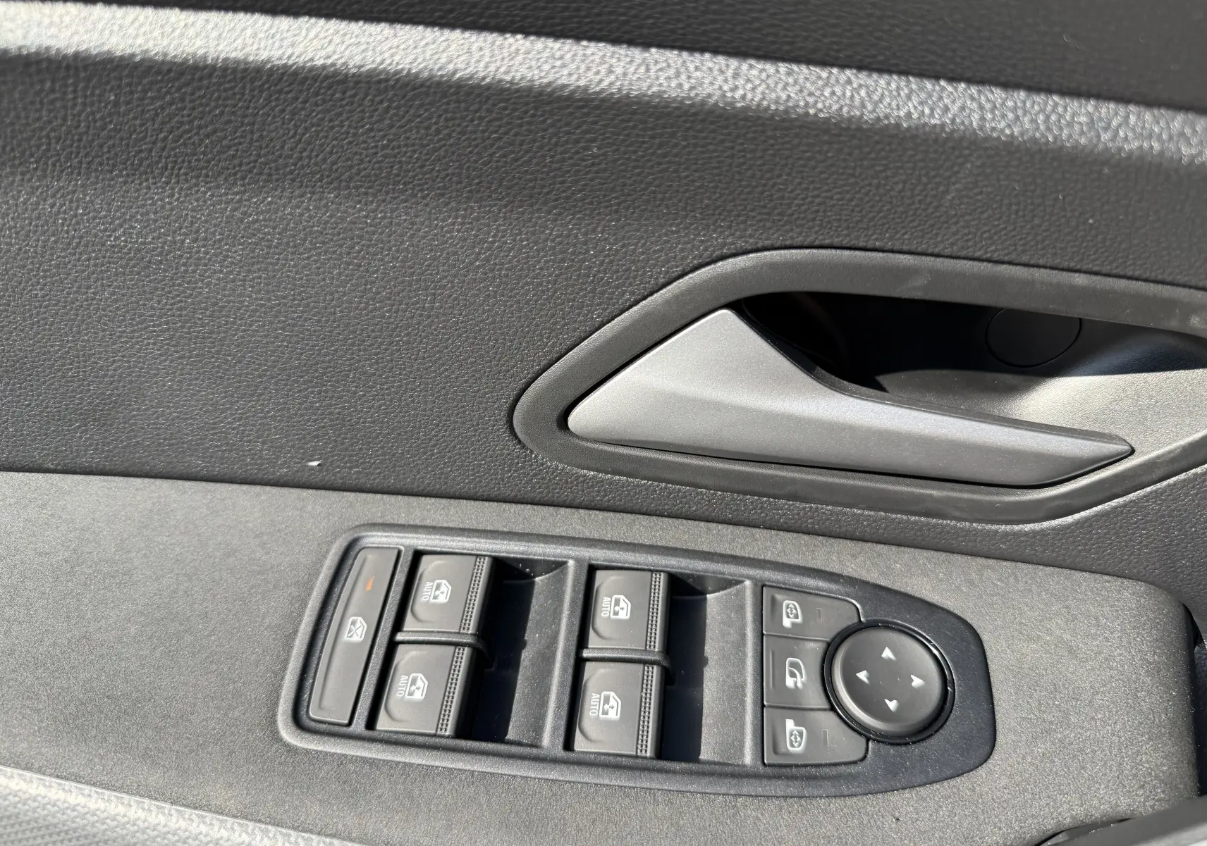 Gros plan sur la commande des vitres et rétroviseurs côté conducteur du Dacia Duster Hybrid 155 blanc glacier, intérieur noir.