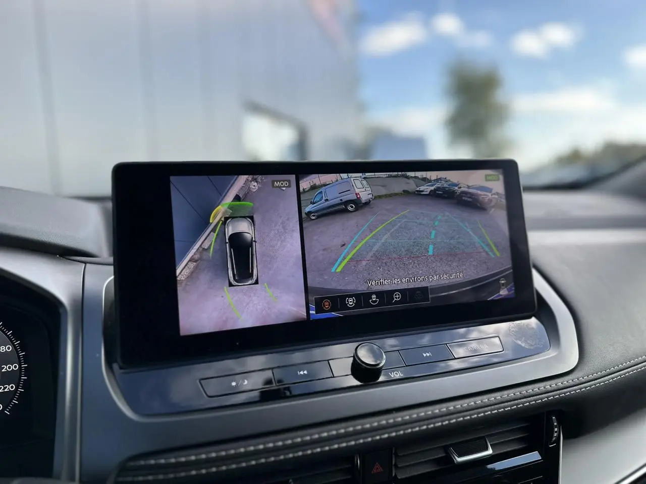 Écran central du Nissan Qashqai blanc nacré montrant la caméra de recul et la vue à 360° du stationnement.