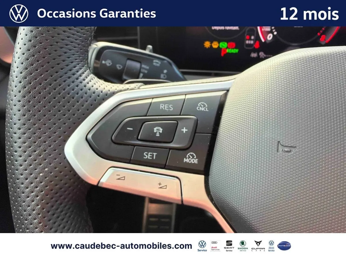 Gros plan sur les commandes multifonctions du volant cuir perforé du Volkswagen T-Roc bleu, version hybride 2026.