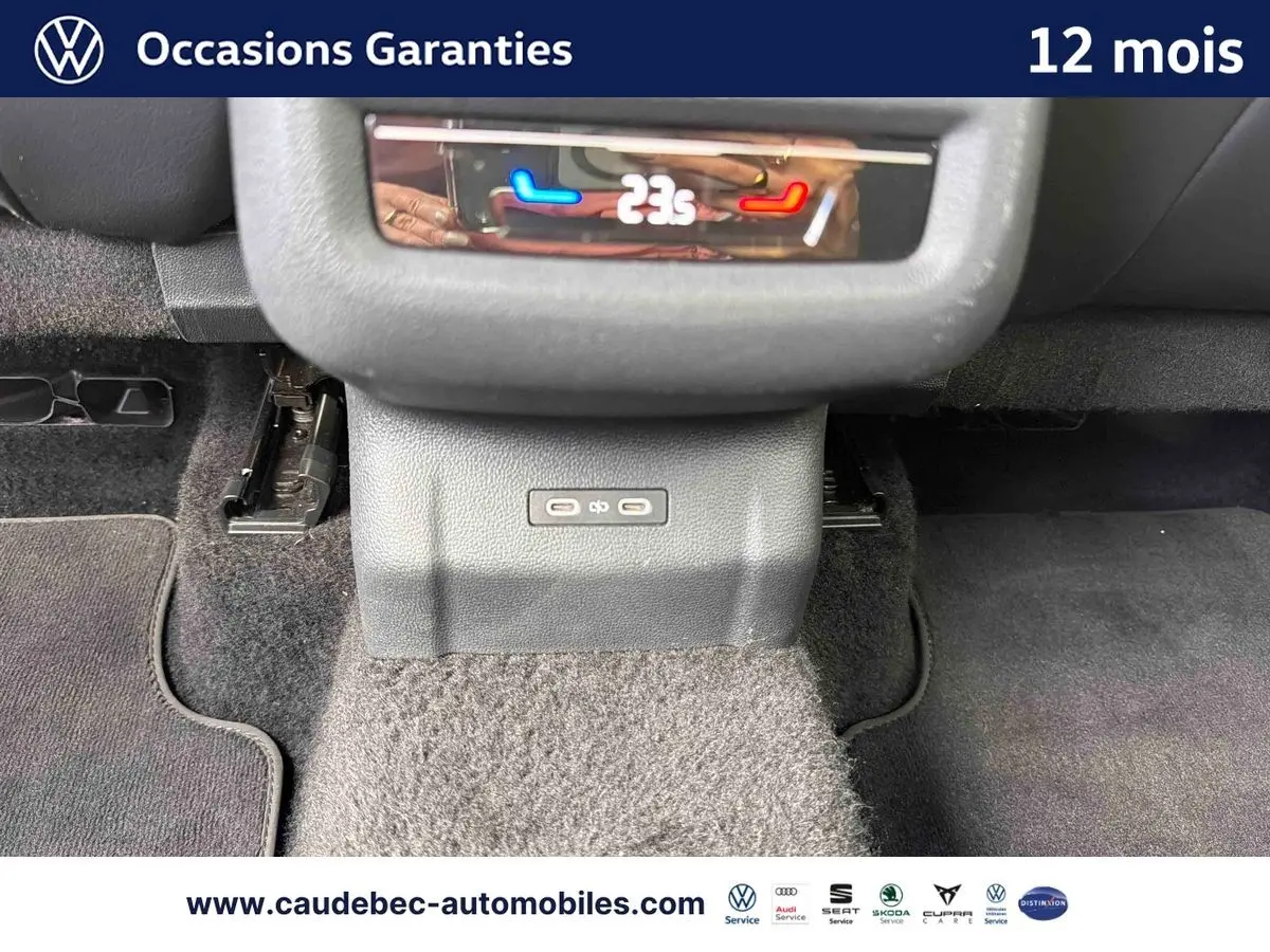 Vue rapprochée de la console centrale arrière du Volkswagen T-Roc bleu, montrant la commande de climatisation digitale à 23°C.