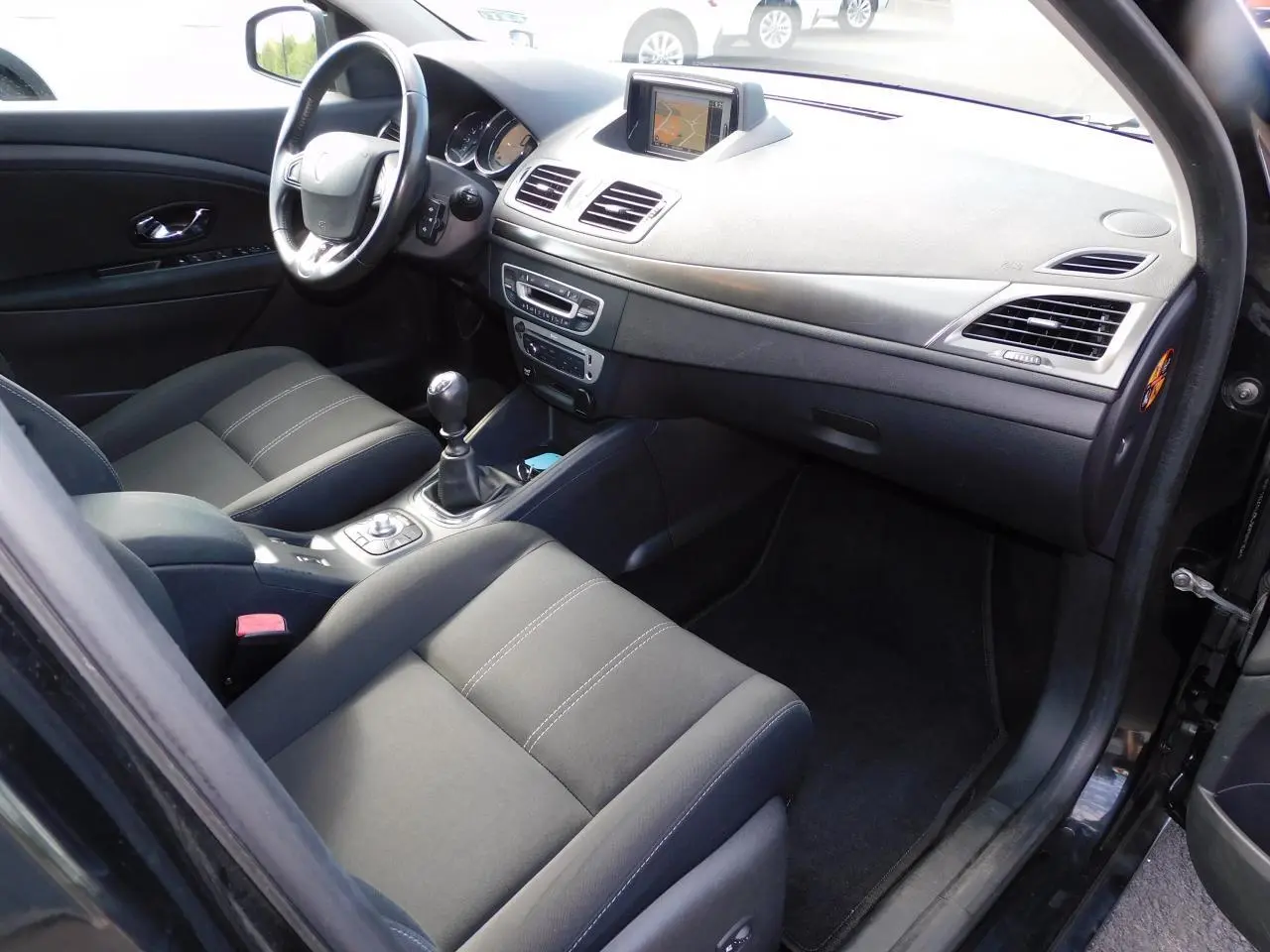 Vue intérieure côté conducteur de la Renault Mégane noire, montrant le tableau de bord avec GPS et la console centrale.