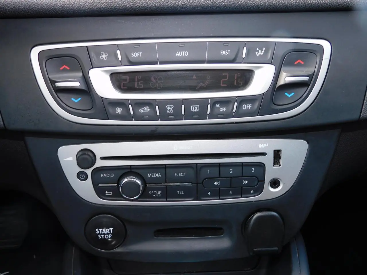 Vue rapprochée de la console centrale noire de la Renault Mégane 2015 avec commandes climatisation et bouton start/stop.