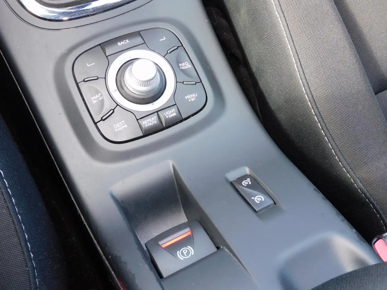 Gros plan sur la console centrale noire de la Renault Mégane 2015, montrant le frein de parking assisté et commandes GPS.