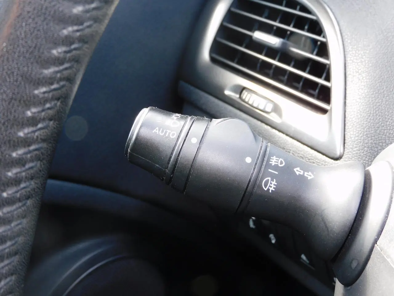 Gros plan sur la commande des feux noirs à gauche du volant dans l'habitacle de la Renault Mégane 2015.