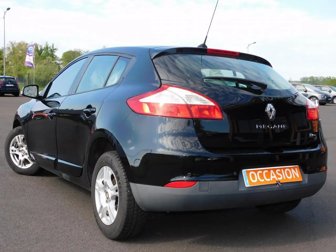 Vue 3/4 arrière droite d'une Renault Mégane noire avec feux arrière allongés et plaque occasion visible
