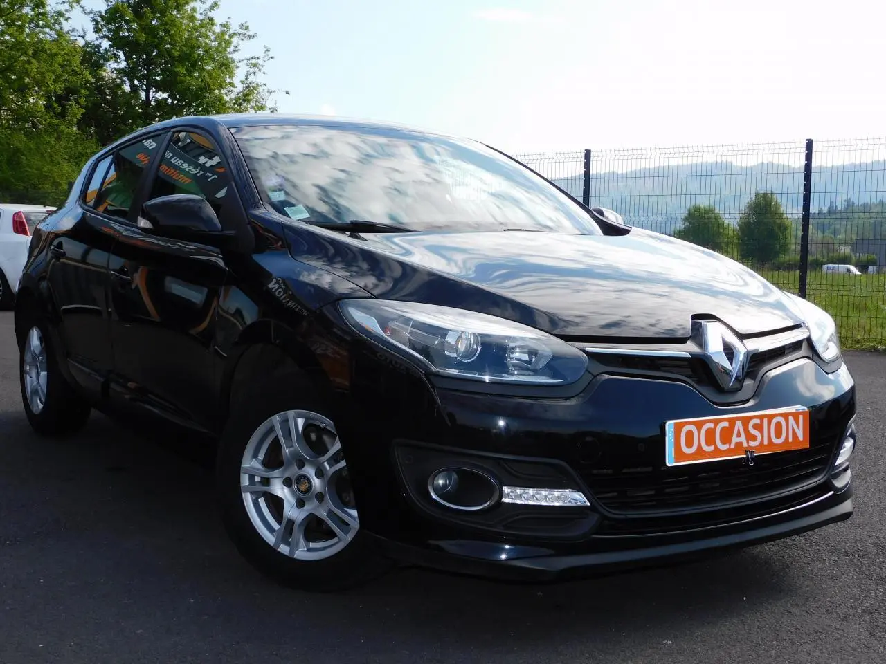 Renault Mégane noire vue de trois quarts avant droit avec phares LED et plaque "OCCASION" visible.