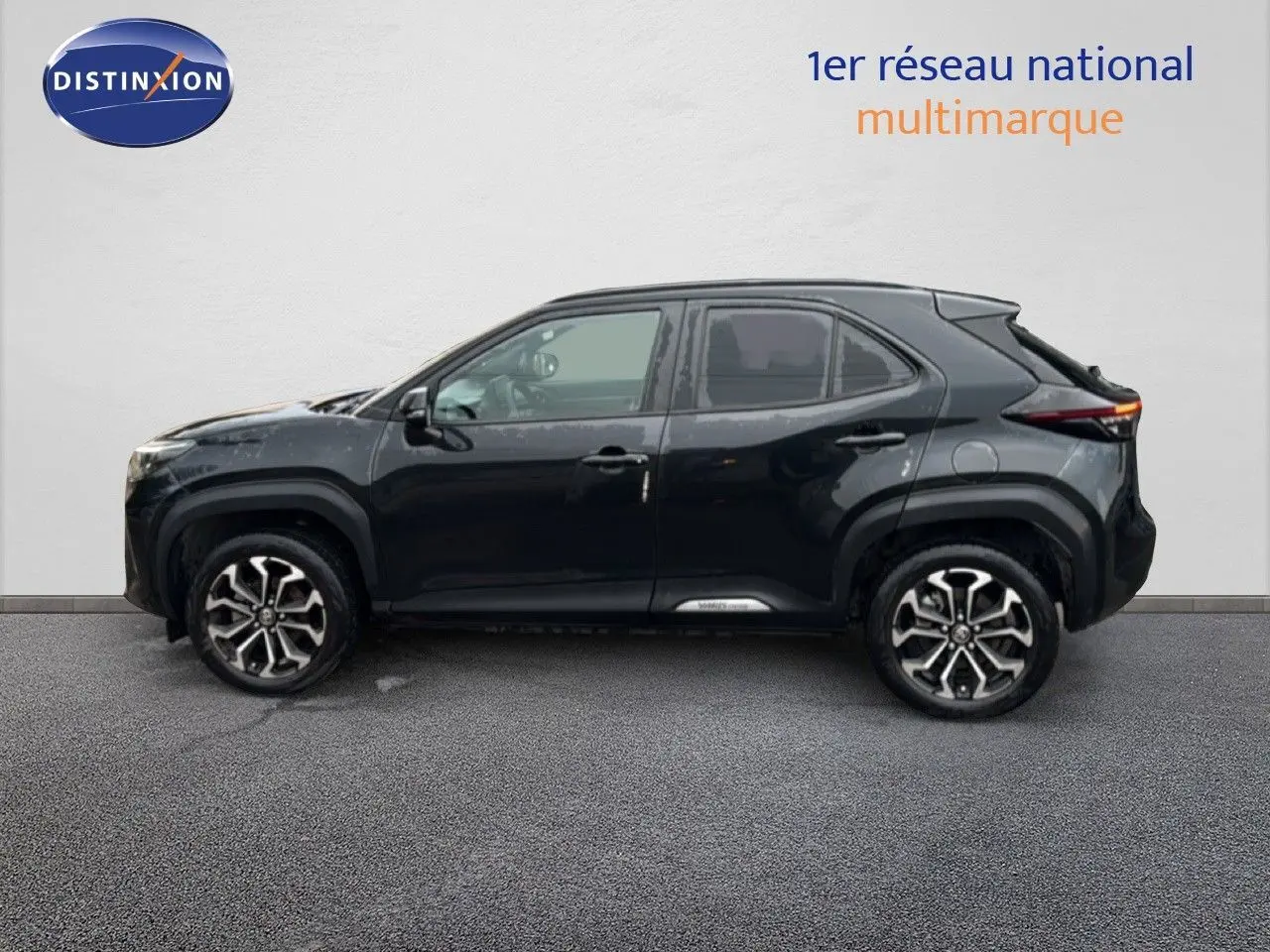 Profil côté gauche de la Toyota Yaris Cross 116h Design noire 2023 avec jantes bi-ton et lignes modernes distinctives.