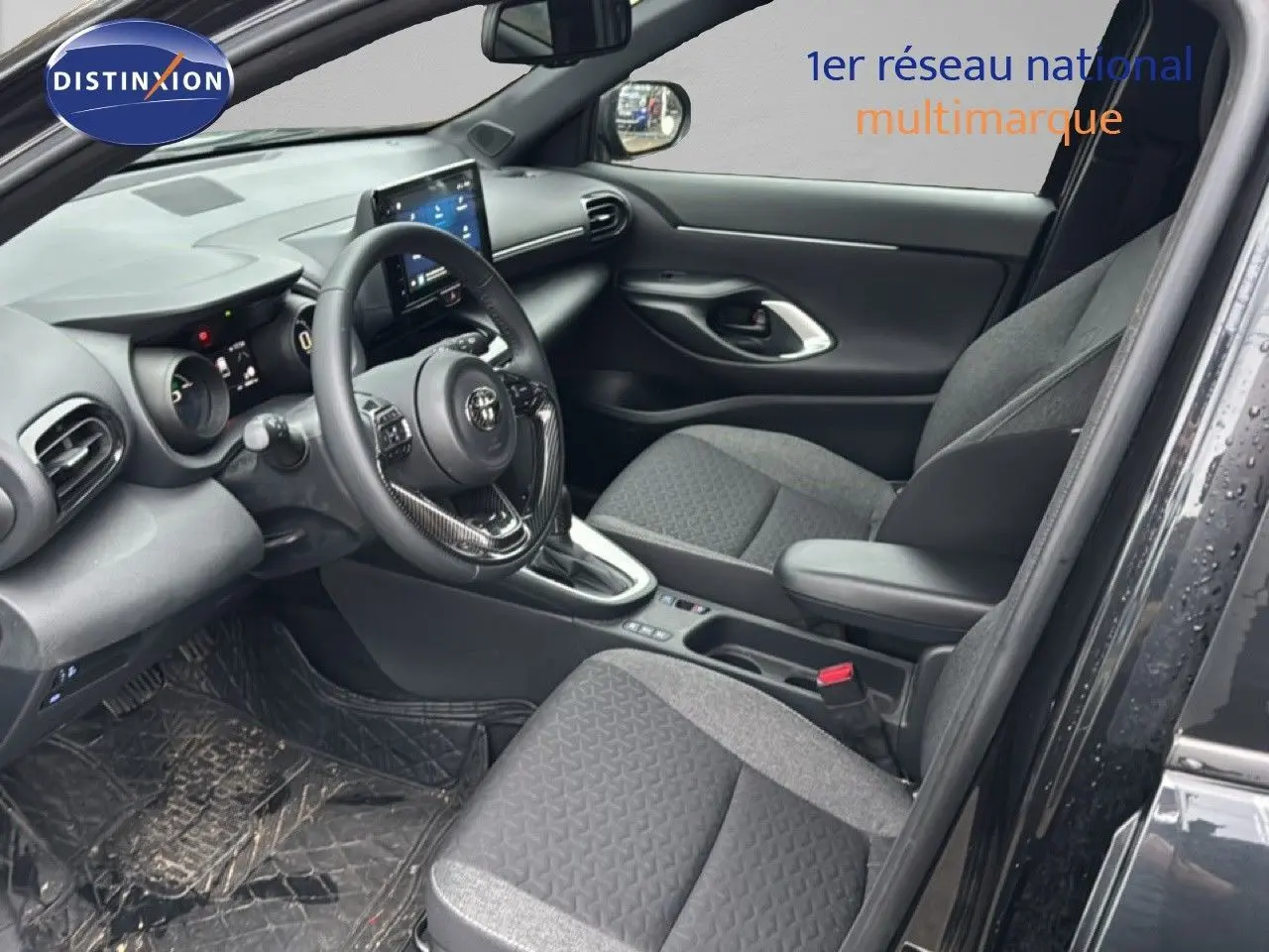 Intérieur côté conducteur de la Toyota Yaris Cross noire 2023, avec tableau de bord et sièges en tissu gris.