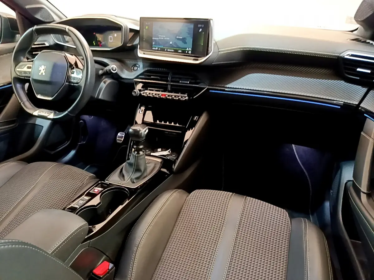 Intérieur de la Peugeot 208 GT Line 2020 vu côté conducteur, tableau de bord noir avec écran tactile et volant cuir.