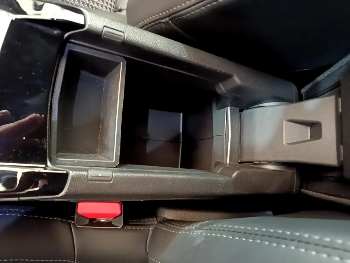 Vue plongeante sur le rangement central noir et la console entre les sièges avant d'une Peugeot 208 GT Line rouge.