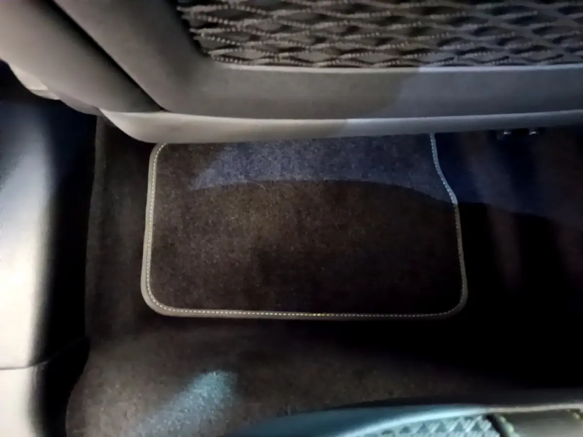 Tapis de sol noir sous le siège arrière gauche d'une Peugeot 208 rouge version GT Line 2020.