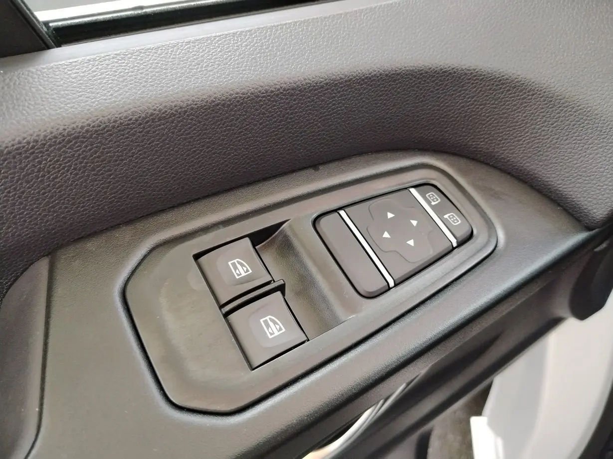 Commandes des vitres électriques et réglage des rétroviseurs sur la portière intérieure d'un Nissan Primastar blanc.