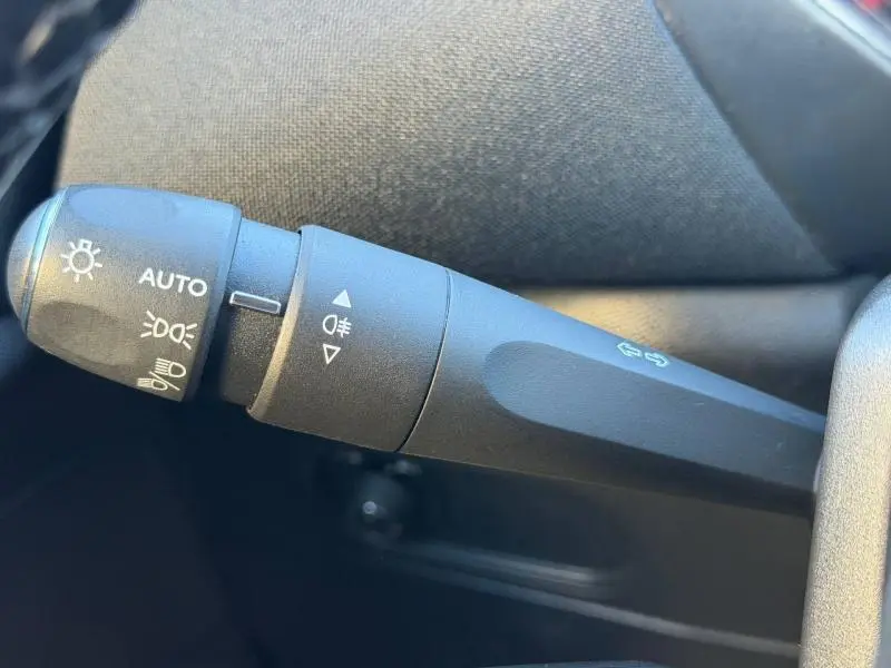 Gros plan sur la commande de phares noire du DS3 Crossback PureTech 100ch Chic, avec pictogrammes blancs visibles.