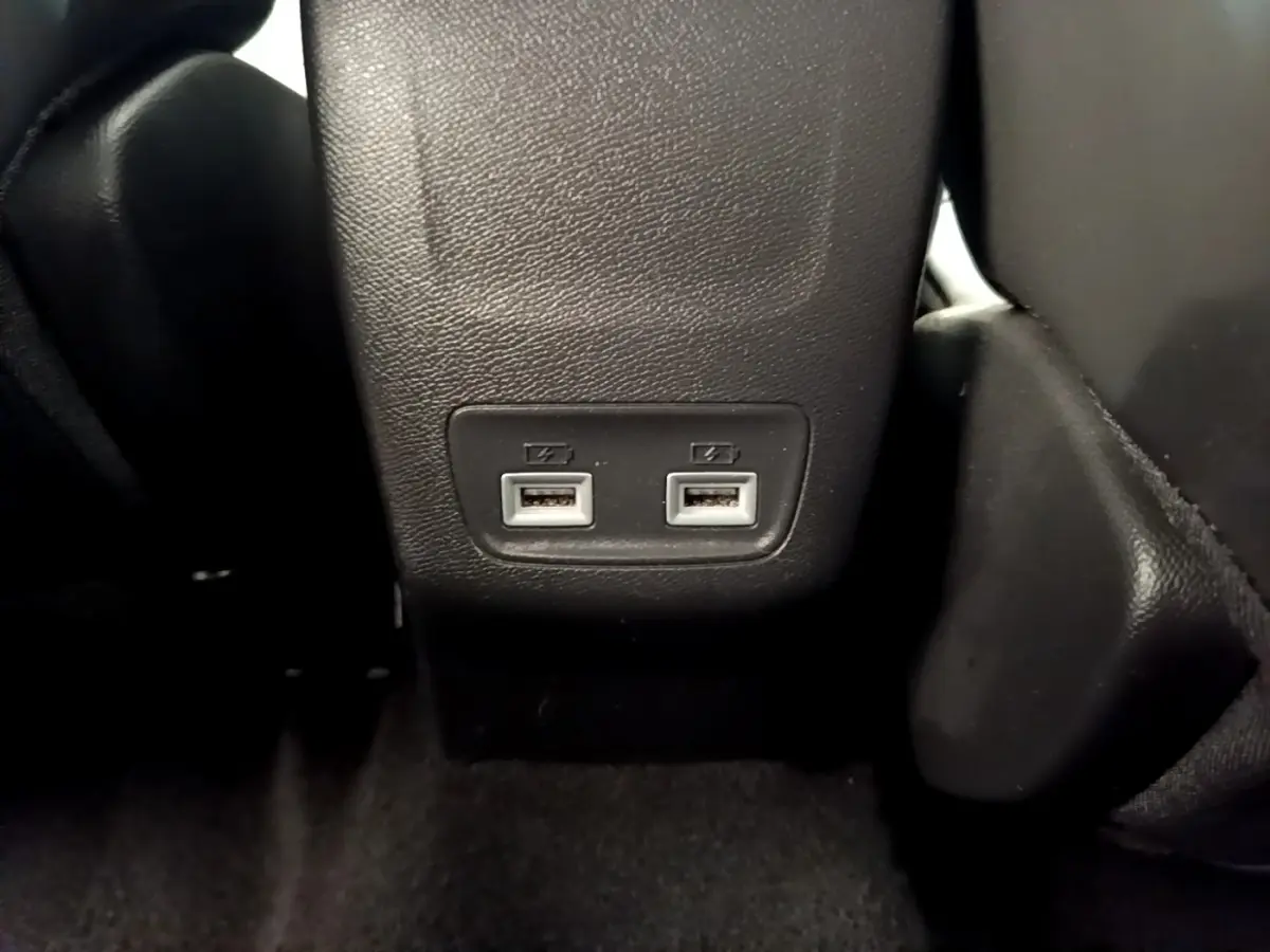 Gros plan sur les deux ports USB arrière intégrés à la console centrale d’une Peugeot 208 blanche.