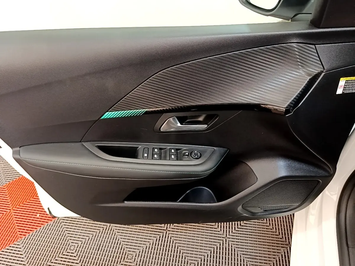 Vue rapprochée de la porte avant gauche blanche du Peugeot 208 avec habillage noir et insert effet carbone.