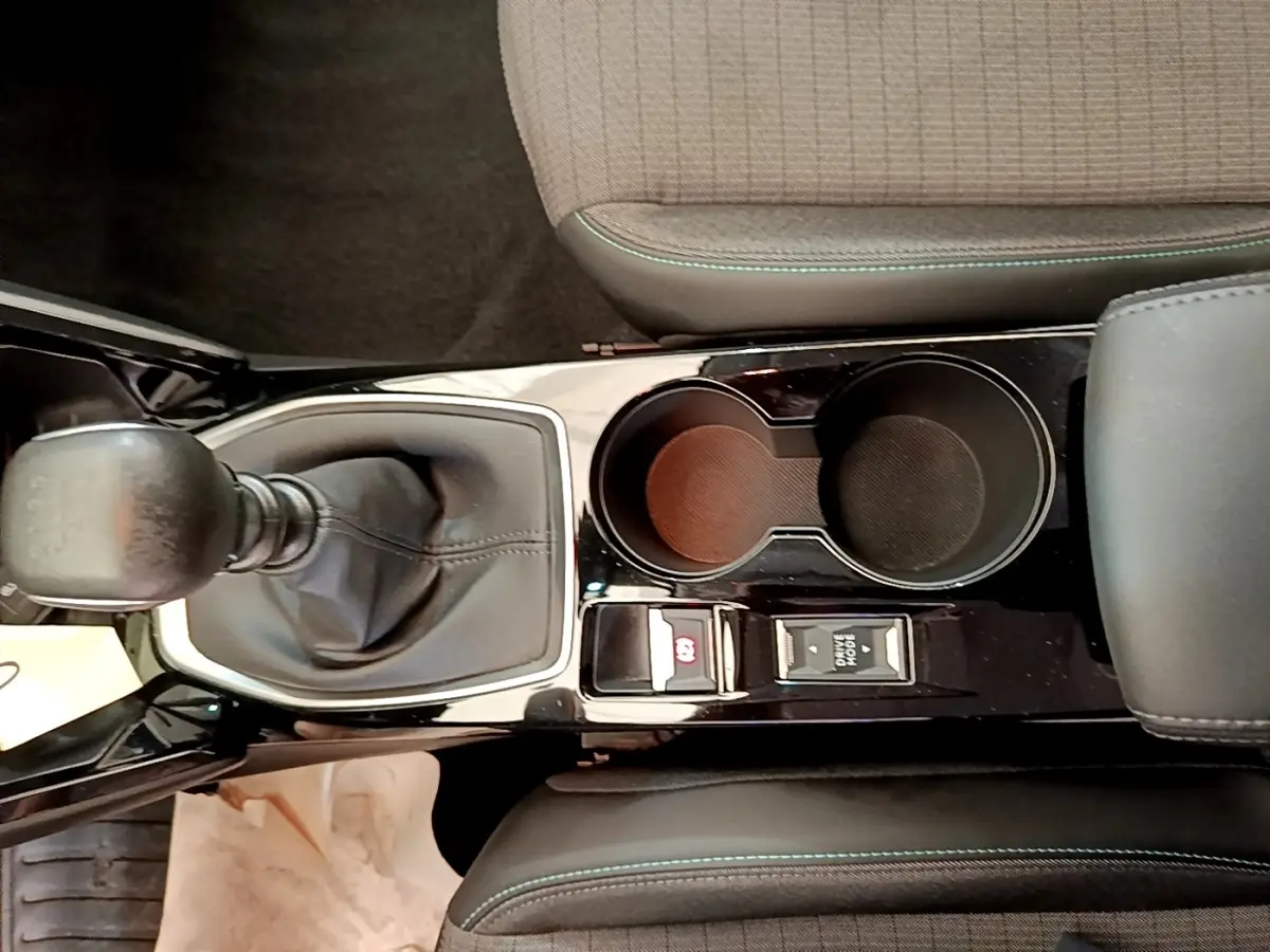 Vue plongeante sur la console centrale noire de la Peugeot 208 blanche, avec levier de vitesse manuel et porte-gobelets.