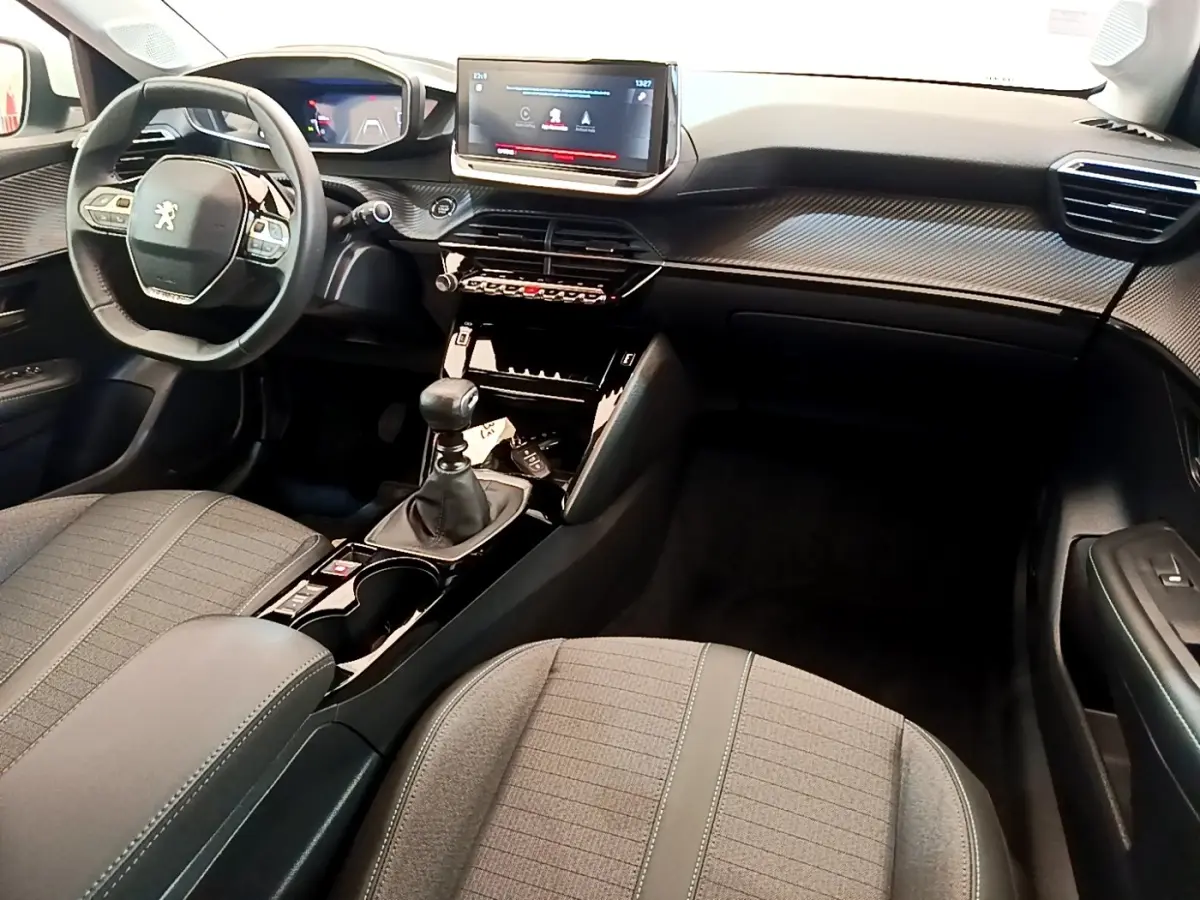 Vue intérieure avant droite du Peugeot 208 PureTech 100 S&S Allure Business 2021 avec tableau de bord noir et écran tactile 10 pouces.