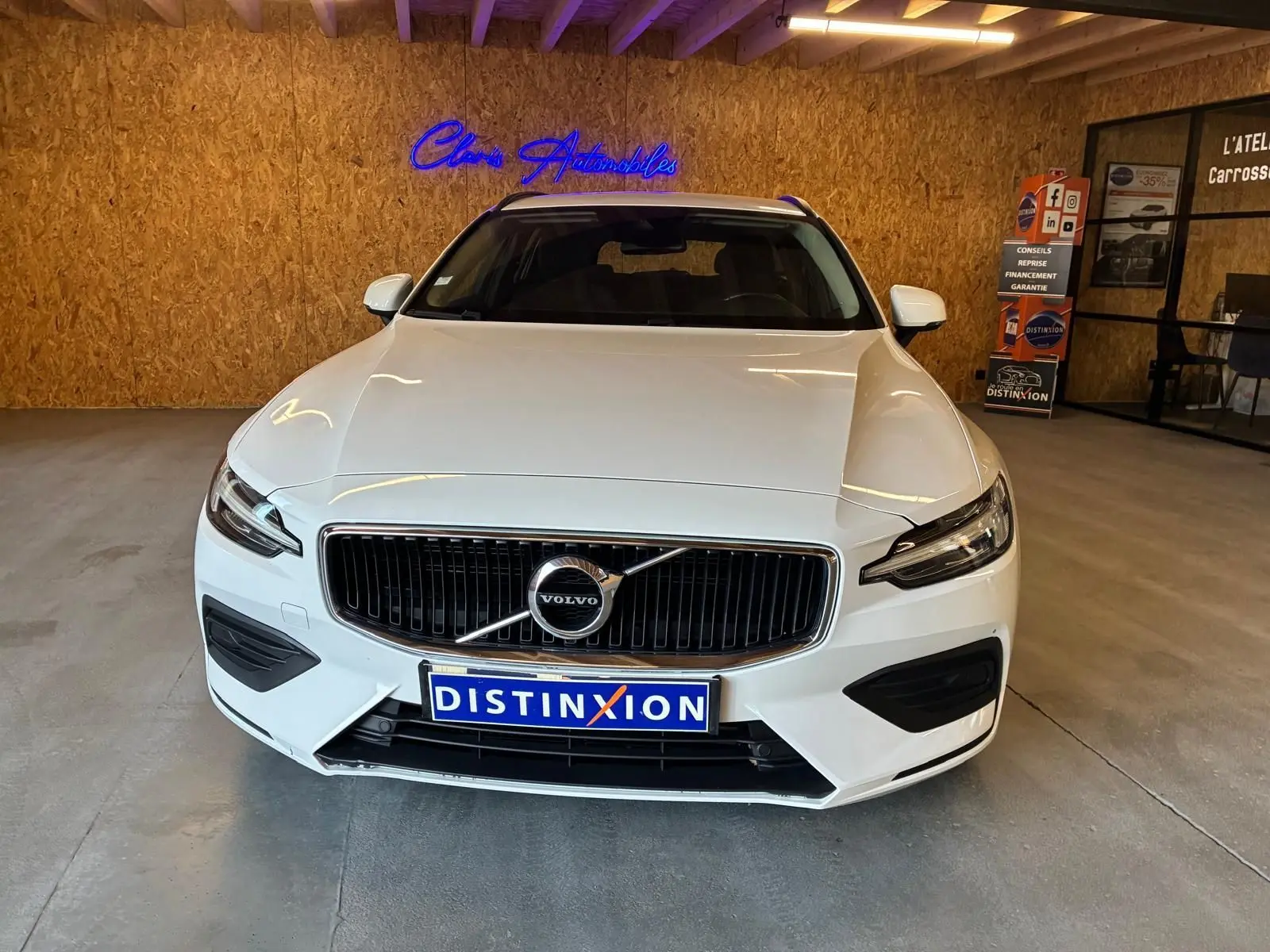 Vue avant d'un Volvo V60 D3 blanc 2020 avec calandre noire et logo centré dans un showroom.