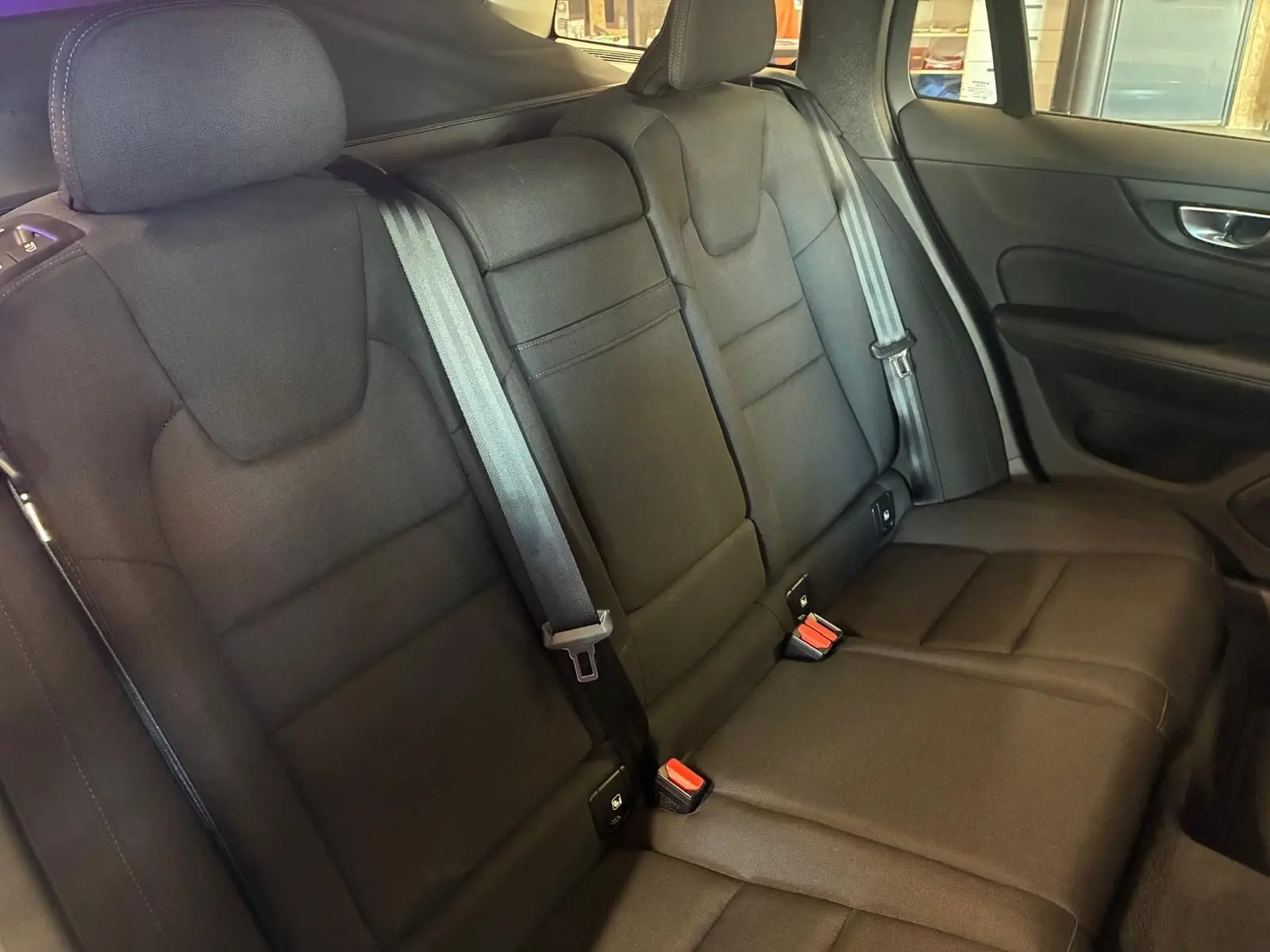 Vue intérieure côté droit des sièges arrière noirs en tissu du Volvo V60 D3 2020, avec ceintures de sécurité visibles.
