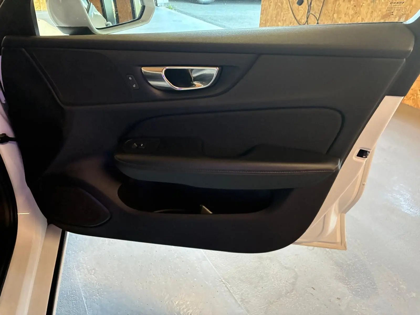 Vue intérieure de la porte avant gauche noire avec poignée chromée d'une Volvo V60 D3 blanche de 2020.