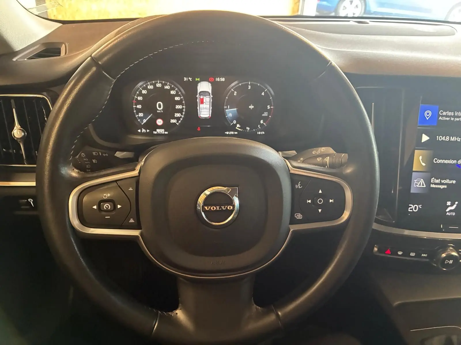 Vue rapprochée du volant noir de la Volvo V60 D3 2020 avec tableau de bord digital et écran tactile central.
